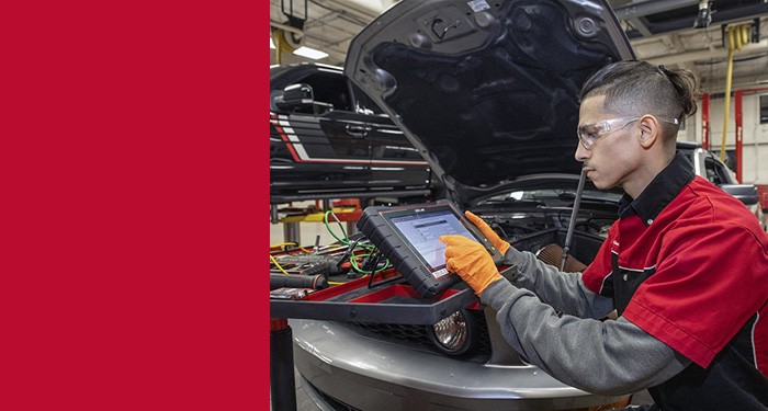 Student working under the hood of a car