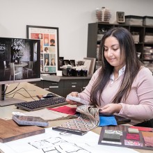 Andrea Nuñez at computer with various interior design sample swatches